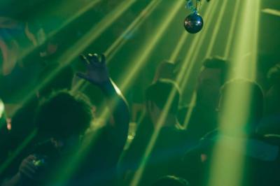 Salle de bar à la décoration punk avec murs graffités, tonneaux métalliques et mobilier en bois et velours rouge.