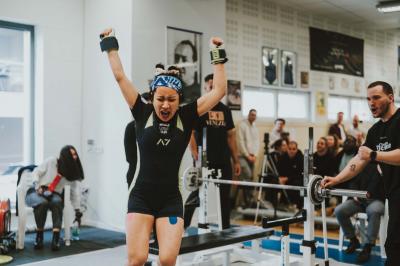 Un homme en costume bleu se tient debout sur une terrasse extérieure par temps nuageux.