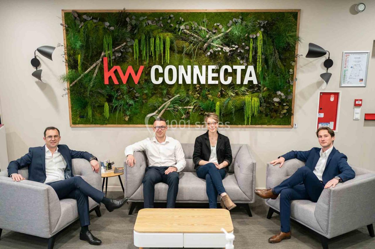 Quatre personnes assises sur des fauteuils dans un espace moderne avec un mur végétal et le logo ’KW Connecta’.
