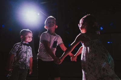 Des personnes en tenue élégante regardent des danseuses en maillot de bain et bonnet, lors d'un événement en extérieur.