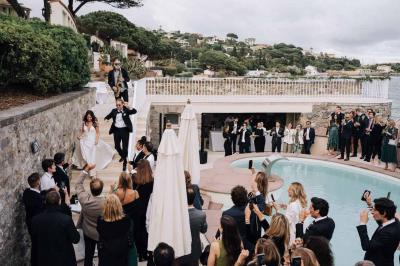 Des personnes en tenue élégante regardent des danseuses en maillot de bain et bonnet, lors d'un événement en extérieur.