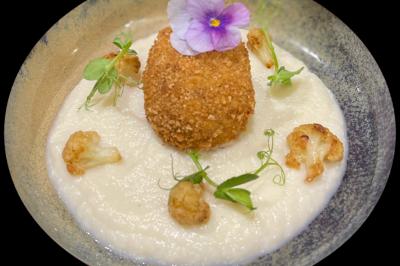 Étang calme entouré d'arbres avec un paysage vallonné en arrière-plan sous une lumière naturelle.