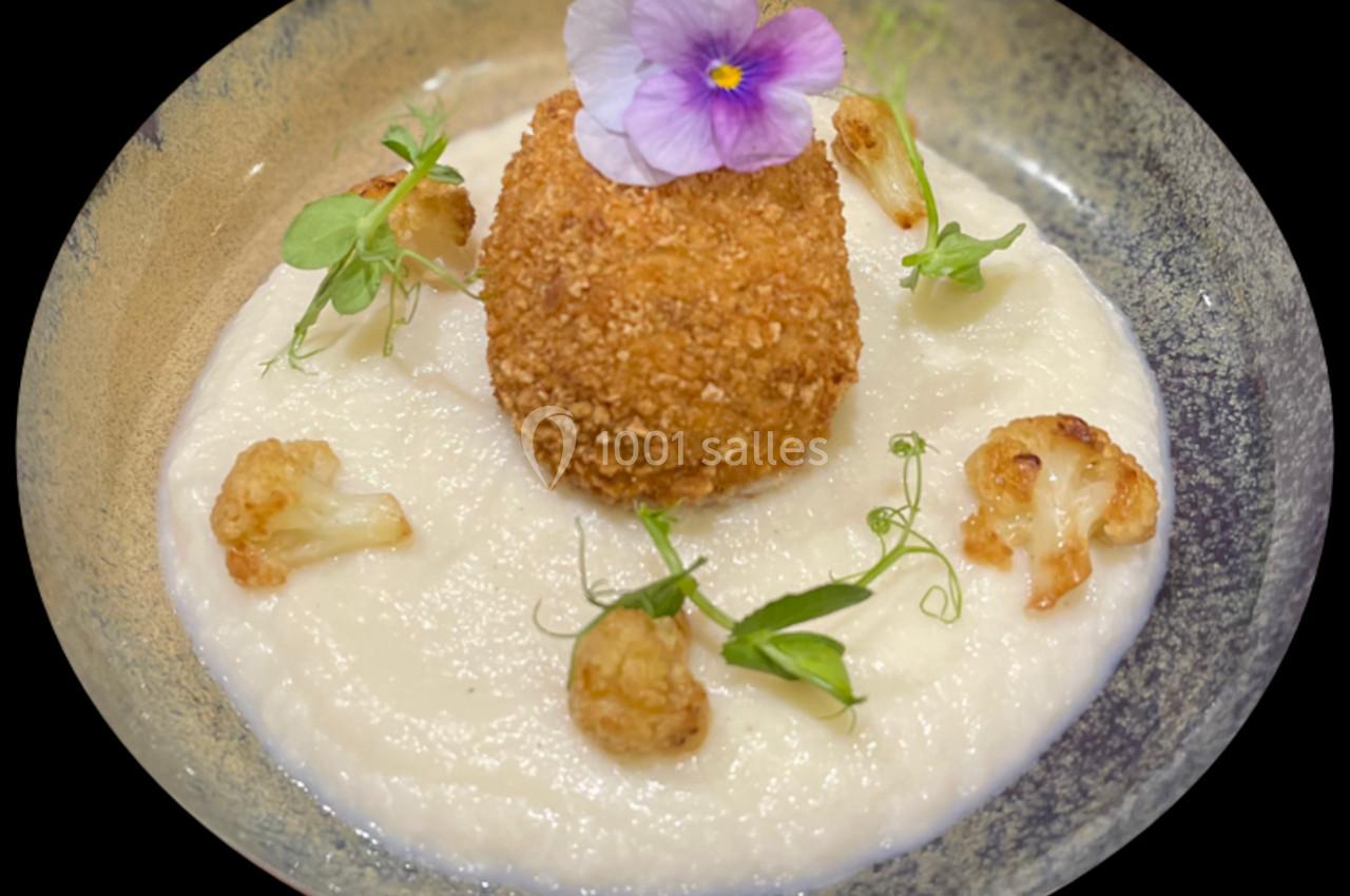 Croquette dorée sur purée blanche, décorée de fleurettes de chou-fleur rôties, micro-pousses et une fleur comestible.