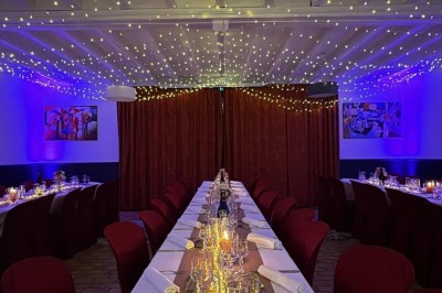 Étang calme entouré d'arbres avec un paysage vallonné en arrière-plan sous une lumière naturelle.