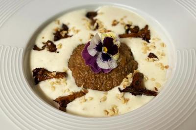 Salle de réception aménagée avec des tables dressées pour un événement, éclairage tamisé et scène en arrière-plan.
