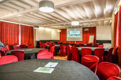 Salle de réception aménagée avec des tables dressées pour un événement, éclairage tamisé et scène en arrière-plan.