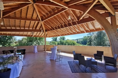 Salle de réception aménagée avec des tables dressées pour un événement, éclairage tamisé et scène en arrière-plan.