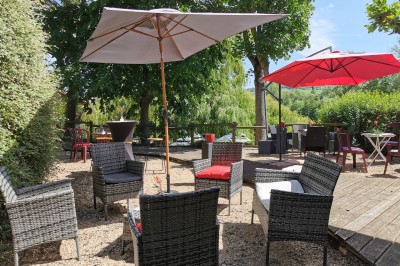 Salle de réception aménagée avec des tables dressées pour un événement, éclairage tamisé et scène en arrière-plan.