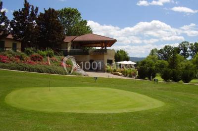 Salle de réception aménagée avec des tables dressées pour un événement, éclairage tamisé et scène en arrière-plan.