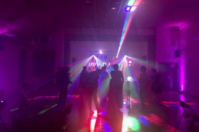 Corset blanc en satin et dentelle, éclairé par des lumières colorées dans un environnement sombre.