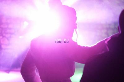 Corset blanc en satin et dentelle, éclairé par des lumières colorées dans un environnement sombre.