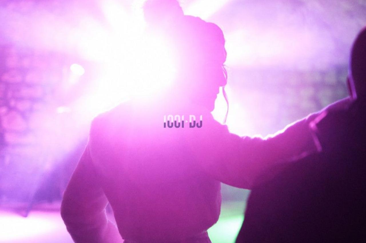 Personne de dos dans une ambiance lumineuse violette sous une voûte, éclairée par des projecteurs.