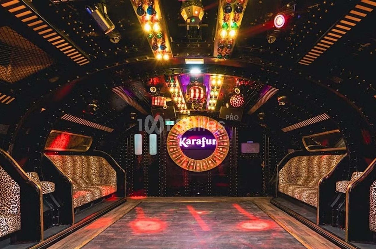 Salle de karaoké colorée avec banquettes à motifs léopard, éclairages vifs et logo ’Karafun’ au fond.