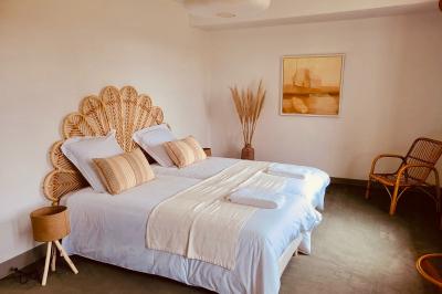 Salon lumineux avec poutres apparentes, canapé blanc, table basse en bois, lampes allumées et vue sur jardin.