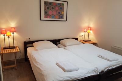 Salon lumineux avec poutres apparentes, canapé blanc, table basse en bois, lampes allumées et vue sur jardin.