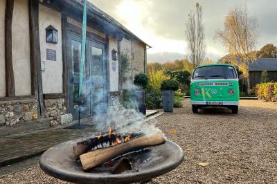 Salon lumineux avec poutres apparentes, canapé blanc, table basse en bois, lampes allumées et vue sur jardin.