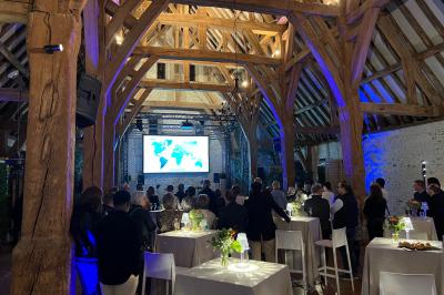 Salon lumineux avec poutres apparentes, canapé blanc, table basse en bois, lampes allumées et vue sur jardin.