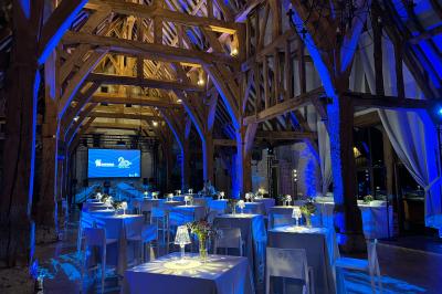 Salon lumineux avec poutres apparentes, canapé blanc, table basse en bois, lampes allumées et vue sur jardin.