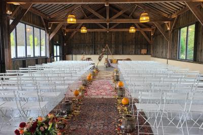 Salon lumineux avec poutres apparentes, canapé blanc, table basse en bois, lampes allumées et vue sur jardin.
