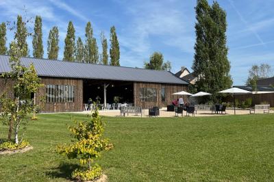 Salon lumineux avec poutres apparentes, canapé blanc, table basse en bois, lampes allumées et vue sur jardin.