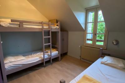 Salle de réunion lumineuse avec tables disposées en U et chaises orange, entourée de grandes fenêtres.