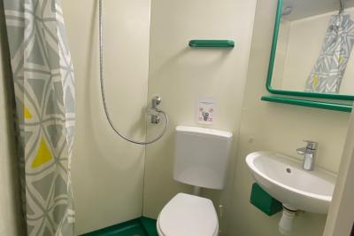 Salle de réunion lumineuse avec tables disposées en U et chaises orange, entourée de grandes fenêtres.