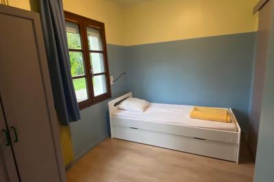 Salle de réunion lumineuse avec tables disposées en U et chaises orange, entourée de grandes fenêtres.