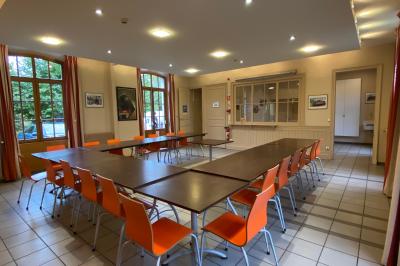 Salon mansardé avec murs violets, deux fauteuils, un canapé rose, une table basse et des étagères remplies de livres.