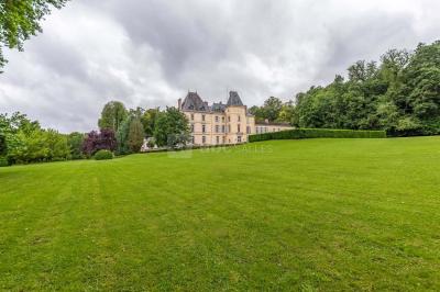 Façade d'un château avec toit en ardoise, entouré de jardins symétriques et allées gravillonnées.