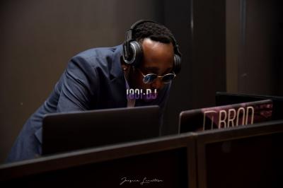 Un DJ portant un casque audio mixe sur son équipement dans un environnement sombre.