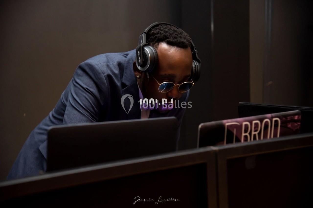 Un DJ portant un casque audio mixe sur son équipement dans un environnement sombre.