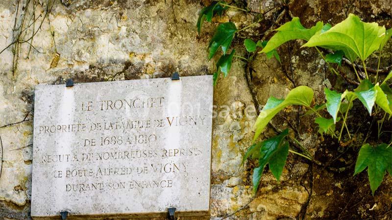 Plaque en pierre fixée sur un mur, entourée de feuilles vertes, avec une inscription évoquant Alfred de Vigny.