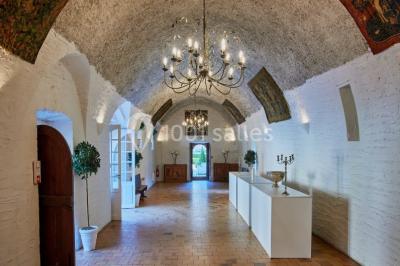 Deux portes en pierre et bois s'ouvrent sur des pièces lumineuses avec mobilier classique et parquet.