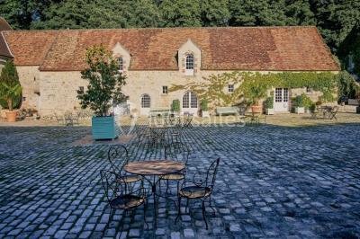 Deux portes en pierre et bois s'ouvrent sur des pièces lumineuses avec mobilier classique et parquet.