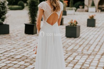 Deux portes en pierre et bois s'ouvrent sur des pièces lumineuses avec mobilier classique et parquet.