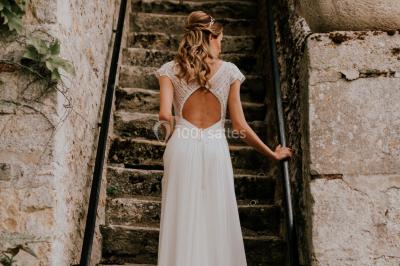 Deux portes en pierre et bois s'ouvrent sur des pièces lumineuses avec mobilier classique et parquet.