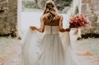 Deux portes en pierre et bois s'ouvrent sur des pièces lumineuses avec mobilier classique et parquet.