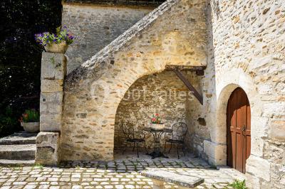 Deux portes en pierre et bois s'ouvrent sur des pièces lumineuses avec mobilier classique et parquet.