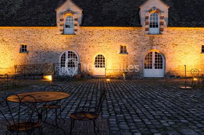 Deux portes en pierre et bois s'ouvrent sur des pièces lumineuses avec mobilier classique et parquet.