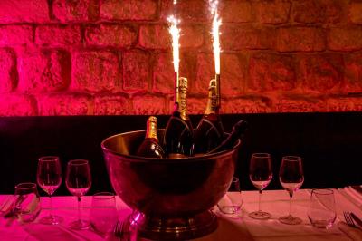 Cocktail jaune orangé garni d’un demi-fruit de la passion, accompagné d’un verre de champagne sur un comptoir en bois.