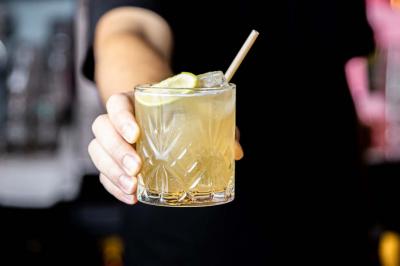 Cocktail jaune orangé garni d’un demi-fruit de la passion, accompagné d’un verre de champagne sur un comptoir en bois.