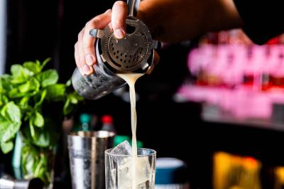 Cocktail jaune orangé garni d’un demi-fruit de la passion, accompagné d’un verre de champagne sur un comptoir en bois.