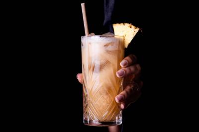 Cocktail jaune orangé garni d’un demi-fruit de la passion, accompagné d’un verre de champagne sur un comptoir en bois.