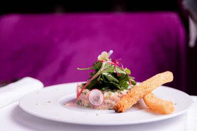 Cocktail jaune orangé garni d’un demi-fruit de la passion, accompagné d’un verre de champagne sur un comptoir en bois.