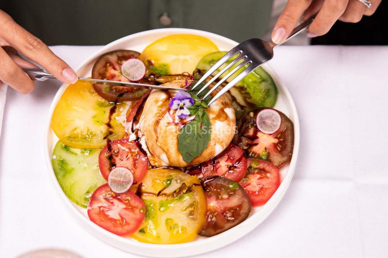 Assiette de burrata garnie de tomates colorées, radis, fleurs comestibles et filet de vinaigre balsamique.