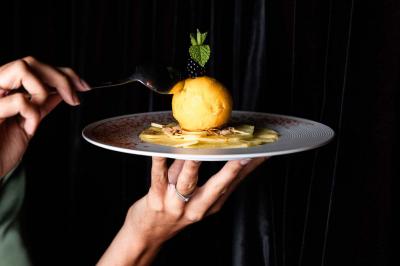 Cocktail jaune orangé garni d’un demi-fruit de la passion, accompagné d’un verre de champagne sur un comptoir en bois.