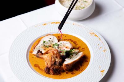 Cocktail jaune orangé garni d’un demi-fruit de la passion, accompagné d’un verre de champagne sur un comptoir en bois.