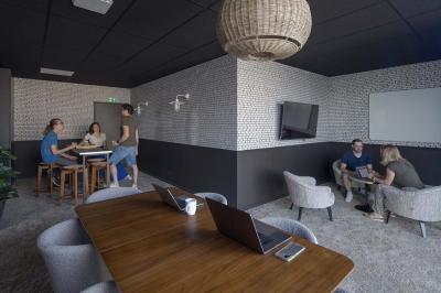 Terrasse moderne avec mobilier extérieur, vue sur une ville au coucher du soleil et ciel aux teintes orangées.