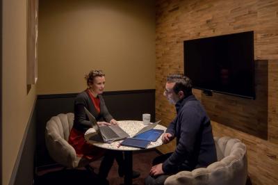 Terrasse moderne avec mobilier extérieur, vue sur une ville au coucher du soleil et ciel aux teintes orangées.
