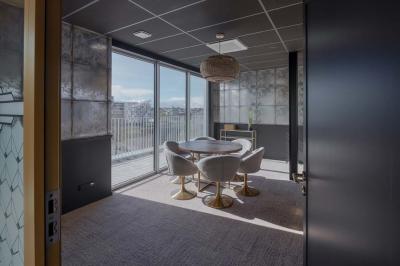 Terrasse moderne avec mobilier extérieur, vue sur une ville au coucher du soleil et ciel aux teintes orangées.